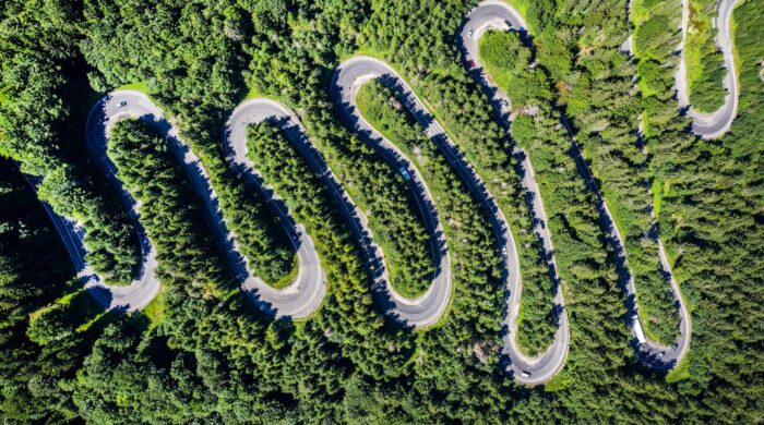 aerial-view-of-a-winding-road-in-green-forest-by-d-7LPT9EK